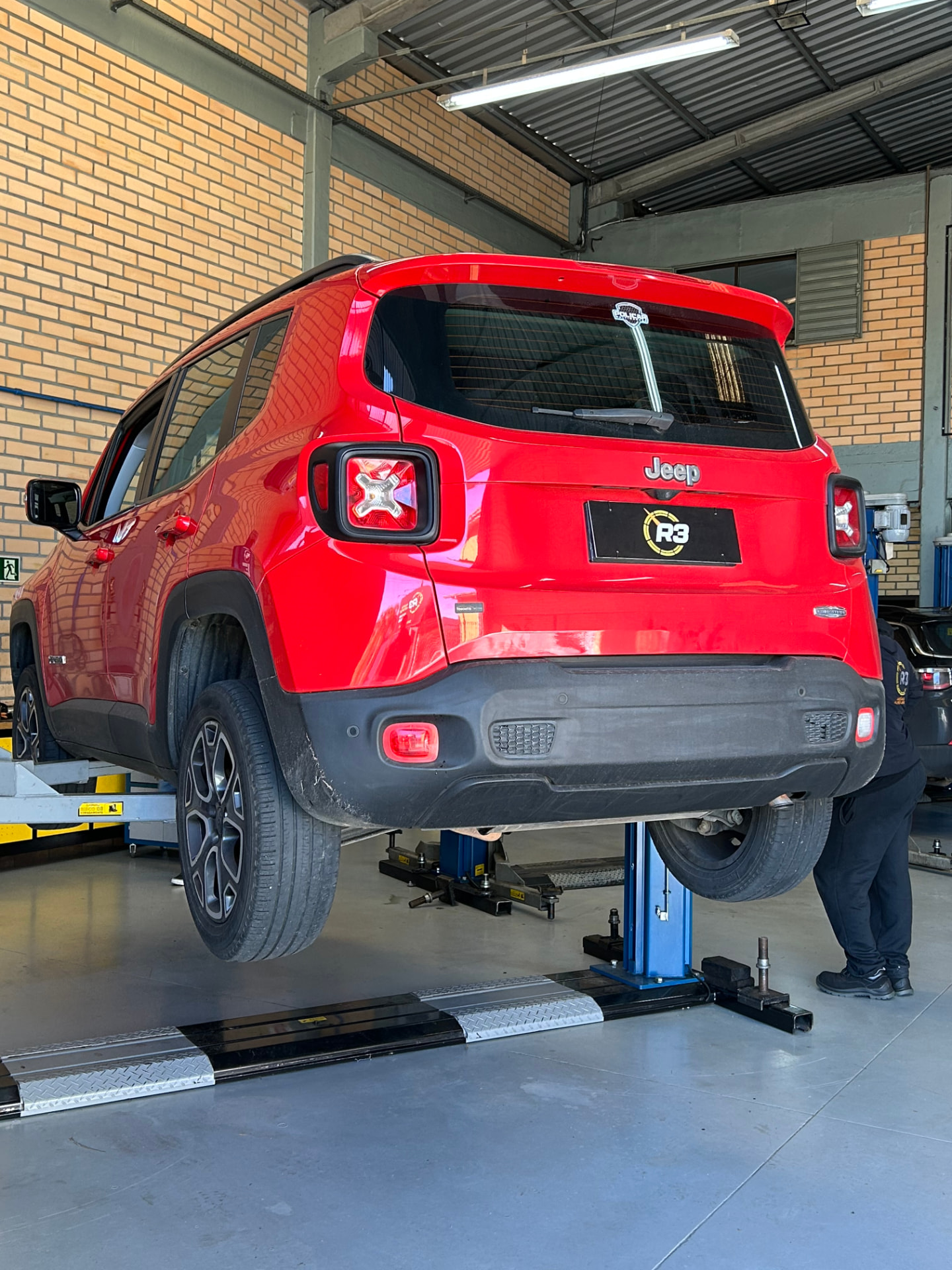 Jeep Renegade vermelho no elevador da oficina